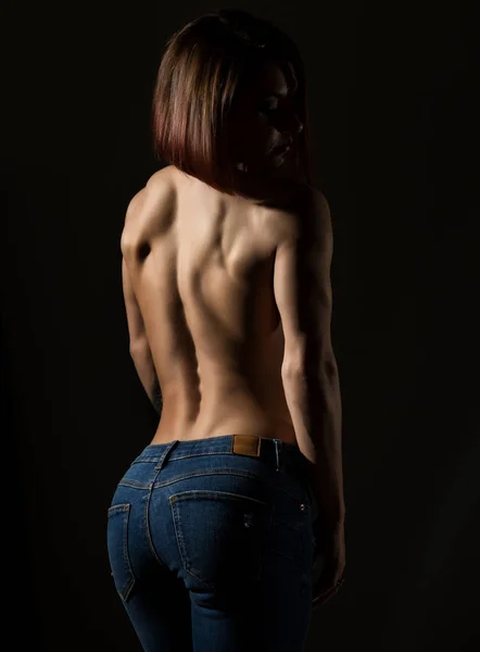 Young female model with muscular body poses on a dark background — Stock Photo, Image