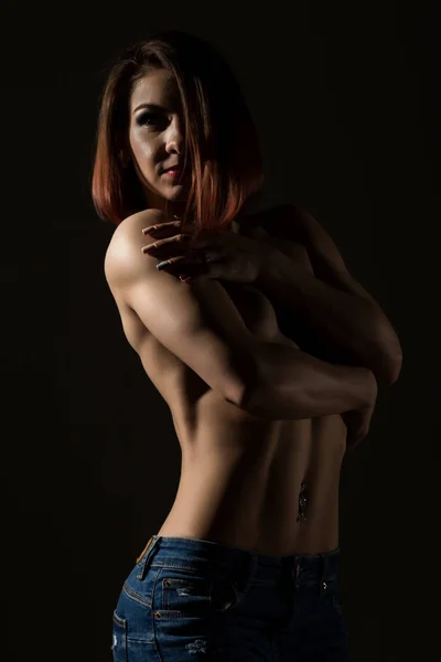 Modelo femenino joven con cuerpo muscular posa sobre un fondo oscuro — Foto de Stock