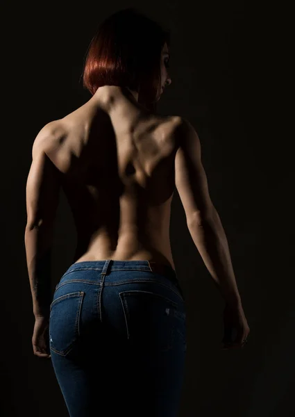 Young female model with muscular body poses on a dark background — Stock Photo, Image