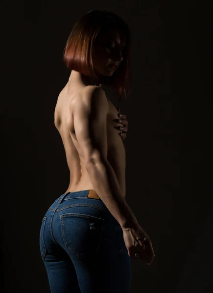 暗い背景に筋肉のついた体のポーズで若い女性モデル — ストック写真