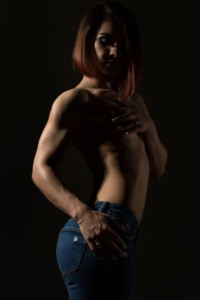 Jeune modèle féminin au corps musclé pose sur un fond sombre — Photo