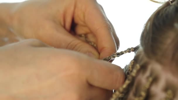 Traditionele Afrikaanse kapsels op blanke vrouwen. professionele kapper weeft spikkels. Slow motion — Stockvideo