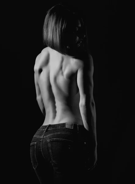 Modelo femenino joven con cuerpo muscular posa sobre un fondo oscuro. blanco y negro — Foto de Stock