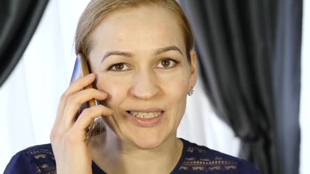 Blond kvinna pratar på en telefon, skrattar glatt — Stockvideo