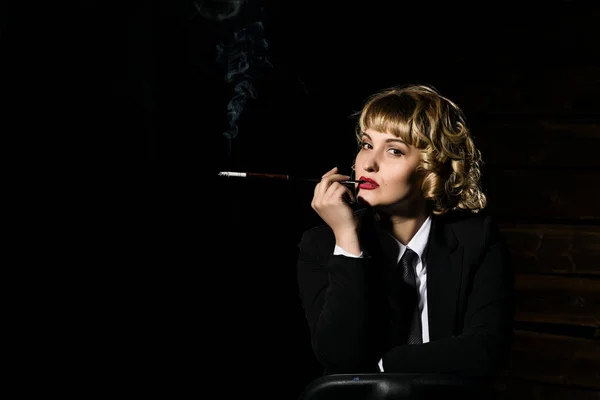 Бизнесвумен с сигаретой на темном фоне, стилизованный ретро-портрет — стоковое фото