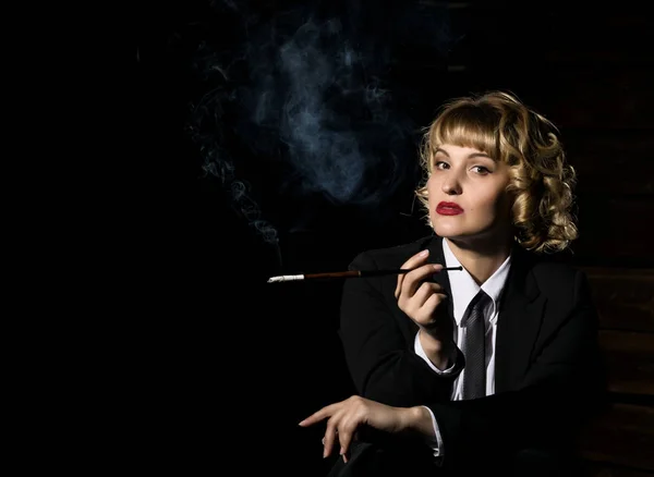 Femme d'affaires avec cigarette sur un fond sombre, portrait rétro stylisé — Photo