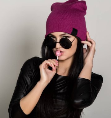 Serin hipster kadın holding lolipop. Kamera mutlu gülümseyerek arayan güzel üniversite öğrenci