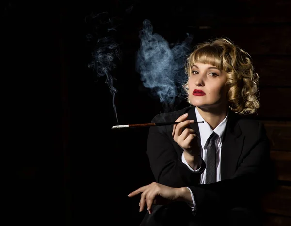 Бізнес-леді з цигаркою на темному тлі, стилізований ретро-портрет. вільний простір для тексту — стокове фото