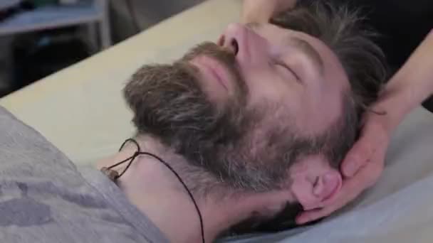 Un homme qui se fait masser le visage. procédure de beauté, prévention du vieillissement de la peau. couché dans le bureau du kasmetologue. rides sur le front — Video