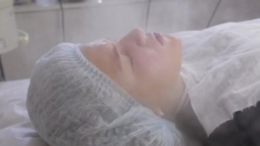 Doktor genç kızın derisini buharla temizler. Güzellik uzmanında sorunlu ciltli genç bir kız. Kozmetoloji kavramı