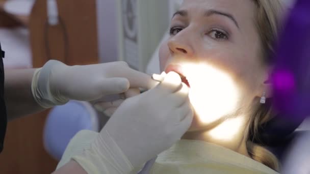 Kadın dişçi, diş kliniğinde bir hastayı tedavi ediyor. Diş muayenesi. Stomatolog hastaların dişlerini tedavi eder. — Stok video