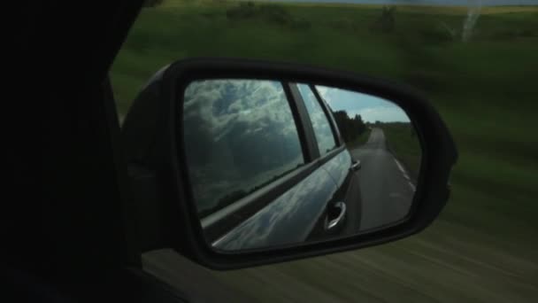 Vista del espejo lateral en un coche, reflejo de nubes y campiña a través del campo en un día de verano — Vídeos de Stock