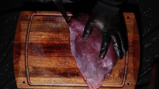 El chef prepara la carne para asarla. las manos de los carniceros cortan cortes de carne con un cuchillo. vista superior — Vídeos de Stock