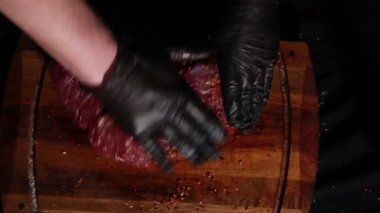 Şef bir parça eti baharatlarla ovuyor, taze çiğ sığır filetosu kesme tahtasına konuyor, kızartılmaya hazır.