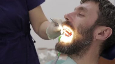 Kadın dişçi, diş kliniğinde bir hastayı tedavi ediyor. Diş muayenesi. Stomatolog hastaların dişlerini tedavi eder.