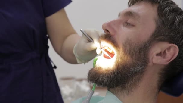Kadın dişçi, diş kliniğinde bir hastayı tedavi ediyor. Diş muayenesi. Stomatolog hastaların dişlerini tedavi eder. — Stok video