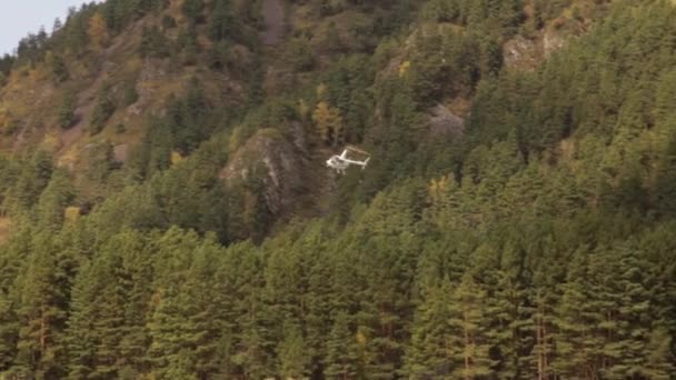 Helikopter dağlık bir bölgedeki bir nehir kıyısına iniyor. İskoçya 'da alçaktan uçan bir helikopter. Küçük hafif havacılık — Stok video