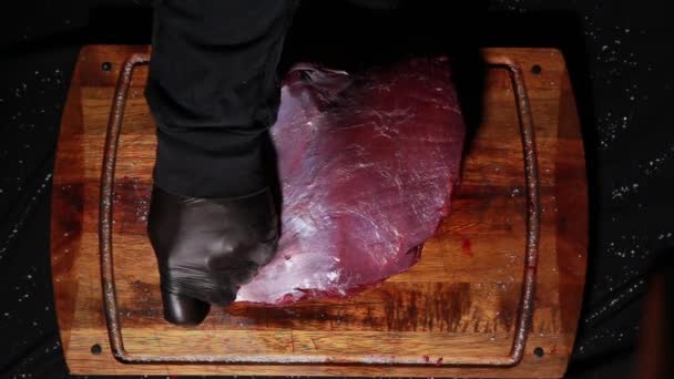 De chef bereidt het vlees voor het roosteren. slagershanden gesneden stukken vlees met een mes. bovenaanzicht — Stockvideo
