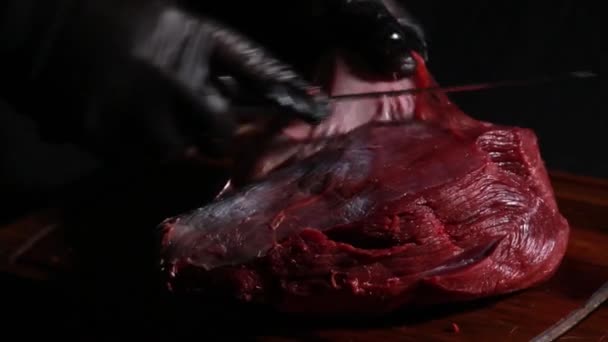 Szef kuchni przygotowuje mięso do pieczenia. rzeźnicy ręce wyciąć kawałki mięsa z nożem — Wideo stockowe