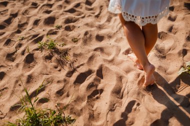 Kumda ayak izleri bırakarak bir sandy üzerinde yürüyen Beach seyahat kadın. Ayrıntı kadın bacakları ve altın kadar yakın