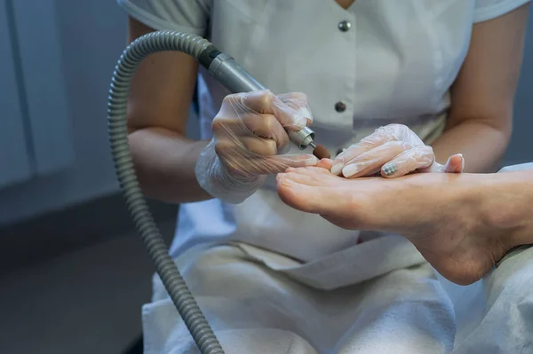 profesional nail technician sanding nails with machine