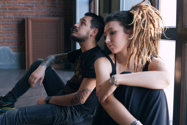 Beautiful young couple sitting back to  on the floor near the window