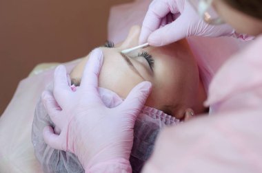 Genç bir kadın yatıyor ve bir Güzellik Salonu Makyaj kaşlarını alır. Kaşları kalıcı makyaj kullanımı. Kaşları ile ana çalışır. Yarı kalıcı makyaj