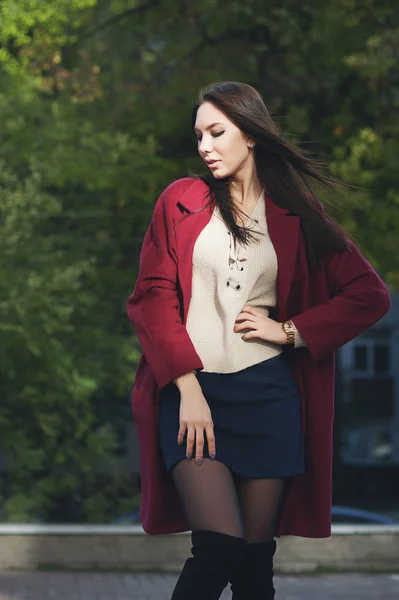 Молодая красивая стильная женщина ходит в бордовом пальто, уличный стиль, весенняя летняя тенденция, темная юбка, бежевая куртка, флирт — стоковое фото
