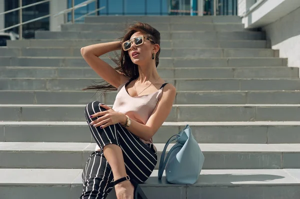 Yeraltı garaja girişte duran güzel genç kadın. Model beyaz bir şerit şık giysiler, bej jersey ve siyah pantolon giyer. Kız arıyor, saç dev