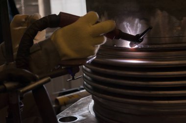 Metal ve kıvılcımlar üreten koruyucu maskeli kaynakçı.