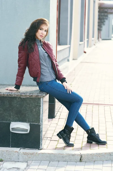 Mulher elegante bonita nova em uma jaqueta de pilotos de Borgonha e jeans azul, estilo de rua, tendência de primavera e outono, olhar, cabelo no vento — Fotografia de Stock