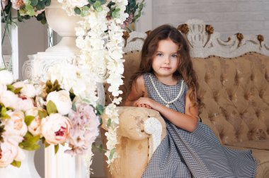 Gülümseyen bir kafeste gri elbiseli küçük bir kız yedi yıllık bir buket peony çiçek, yanında oturan kumral, kıvırcık. Bir tatil kavramı