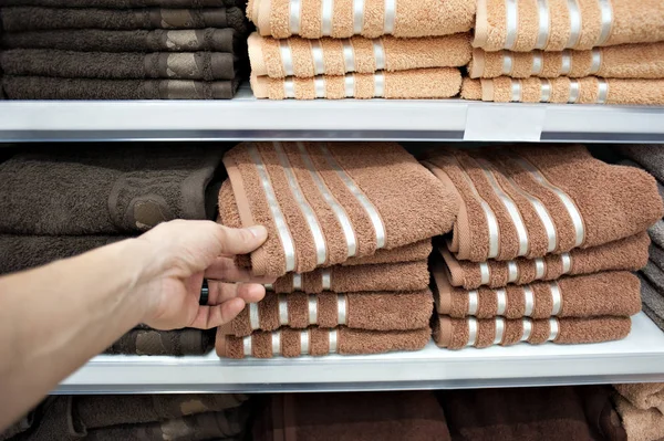 El comprador toma toallas de baño en colores de la cama desde el mostrador de la tienda. Venta — Foto de Stock