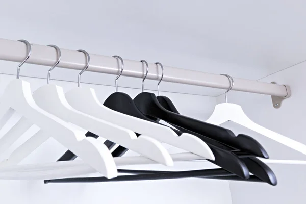 White and black empty clothes hangers, in the wardrobe — Stock Photo, Image