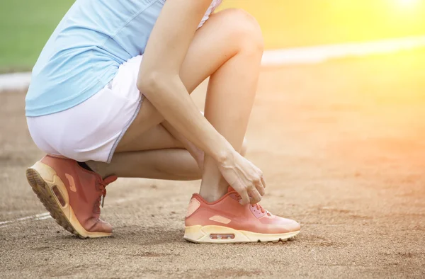 Young woman tying laces of running shoes before training — Stock Photo, Image