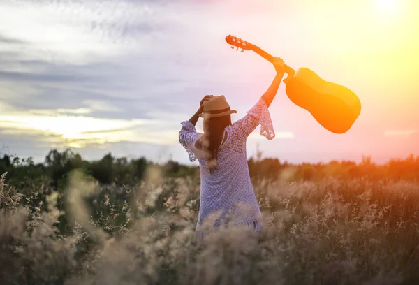 Frau glücklich mit Gitarre auf der Wiese. Reise und Sonnenuntergang, weicher und ausgewählter Fokus — Stockfoto