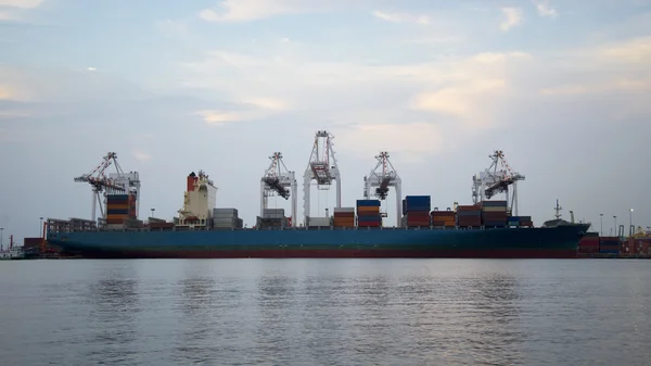 Navio de carga de contêiner com ponte de guindaste de trabalho no estaleiro ao entardecer para importação logística Fundo de exportação, selecione o foco — Fotografia de Stock