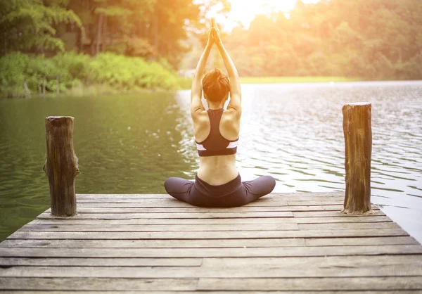 Ung frisk kvinna utövar yoga på bryggan i naturen — Stockfoto
