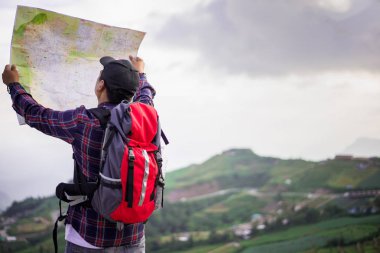 Sırt çantası ile kayıp hiker vahşi alanda yön bulmak için harita denetler