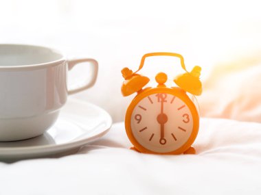 Taze sabah kahvesi ve saat yatakta.