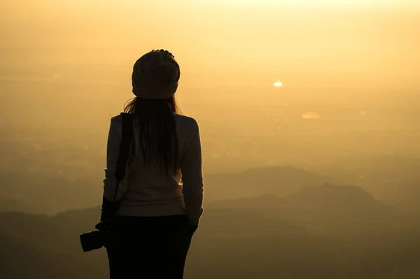 Kuru ot alanında gündoğumu üzerinde duran bir kadın fotoğrafçı silüeti — Stok fotoğraf