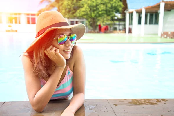 Jovem mulher de chapéu grande relaxante na piscina — Fotografia de Stock