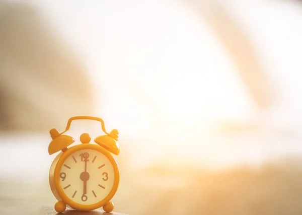 Relógio despertador na cama de manhã com luz do sol, cama de fundo, vintage — Fotografia de Stock