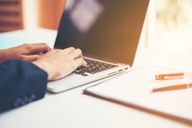 Masasında enstrümanlar, planlar ve dizüstü bilgisayarlarla oturan genç bir kadın.