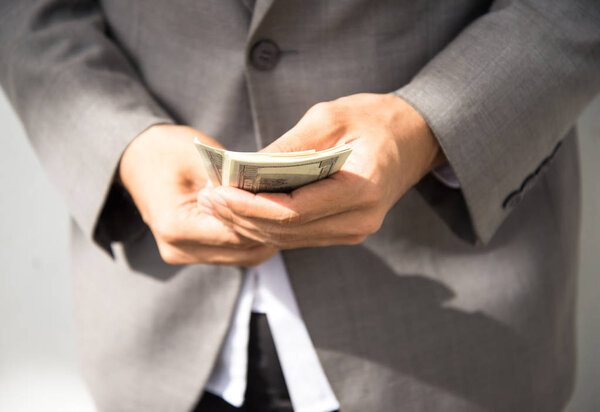 Business executive in formal suit giving money as a bribe, select focus