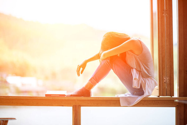Молодая привлекательная женщина, сидя на окне, одинокое настроение

