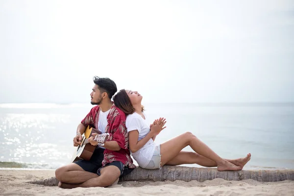 可爱的西班牙裔夫妇玩吉他唱小夜曲的爱和拥抱在海滩上 — 图库照片
