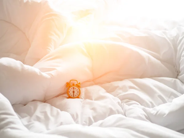Reloj despertador en la cama por la mañana con luz solar — Foto de Stock