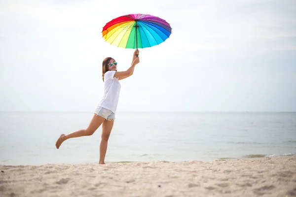 Młode kobiety skoki z parasolem i szczęśliwy na plaży — Zdjęcie stockowe