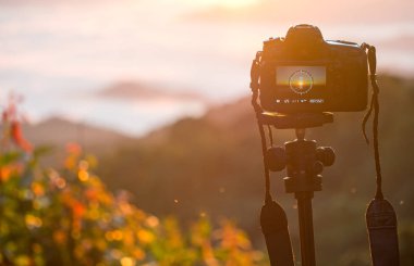 Açık havada bir tripod üzerinde kamera closeup. Arka plan manzara odak dışı
